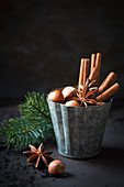 Hazelnuts, star anise and cinnamon sticks in a vintage tin mould on dark background