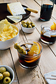 Wermut Cocktails mit Olivenspieß, Chips und Käse