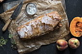 Sharp knife lying on parchment near delectable pumpkin and apple strudel