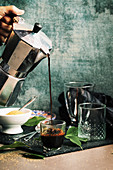 Kaffee aus Espressokanne in Glas gießen
