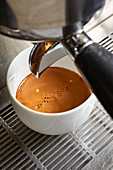 Cremiger Kaffee rinnt aus Kaffeemaschine