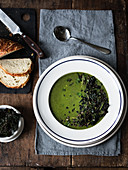 Spinach soup garnished with sauteed lentils, kale crisps, pasley and lemon zest