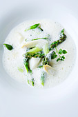 White asparagus foam soup with green and white asparagus tips