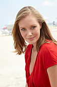 A blonde woman on a beach wearing a red top