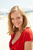 A blonde woman on a beach wearing a red top