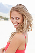 A young blonde woman on a beach wearing a red summer dress