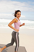 A young brunette woman jogging by the sea wearing sports clothes
