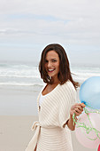 A brunette woman wearing a short-sleeved cardigan and holding a balloon