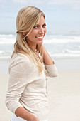 A blond woman on a beach wearing a light cardigan