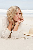 A blond woman on a beach wearing a light cardigan