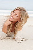 A blond woman on a beach wearing a light cardigan