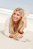 Blonde Frau in hellem Cardigan und Shorts am Strand