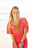 Blonde Frau in rotem Kleid am Strand