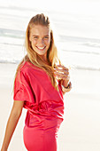 Blonde Frau in rotem Kleid am Strand