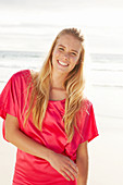 Blonde Frau in rotem Kleid am Strand