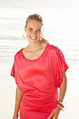 Blonde Frau in rotem Kleid am Strand