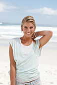 A blonde woman on the beach wearing a light t-shirt