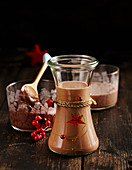 Homemade gingerbread liqueur in a glass with nut-nougat cream spread behind it