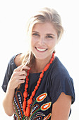 A young blonde woman with necklace wearing a beach dress