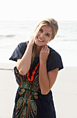 A young blonde woman with necklace wearing a beach dress