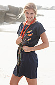 A young blonde woman with necklace wearing a beach dress