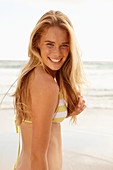Blonde Frau in weiß-gelbem Bikini am Strand