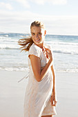 Blonde Frau in weißem Kleid mit Stickerei am Meer