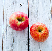 Two red apples on a wooden surface