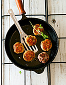 Meatballs in a pan with a sprig of marjoram