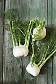 Three fennel bulbs on a wooden surface