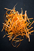 A pile of carrot peel on a black background