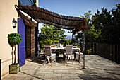 Marble table and wicker chairs on thatched terrace of a French country house