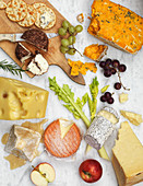 A variety of cheeses with fruits and crackers on a marble background