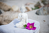 Buddhafigur mit Blüte auf Handtuch