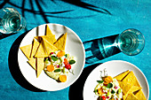 Oregano-Hummus mit Feta serviert mit Crackern auf blauem Untergrund