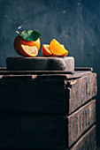 Frische Orangen, ganz und geschnitten, auf Holzkiste