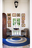 Maritime seating area by the window with blue and white carpet, wicker chairs and boat model on small table