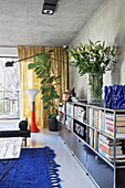 Bücherregal mit Lilienstrauß im Wohnzimmer mit Betondecke