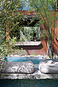 Floor cushion by the pool in front of the house with a rusty facade