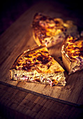 Three pieces of bacon quiche on a wooden board