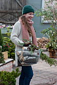 Woman carrying basket with firewood and branch of hemlock tree