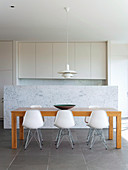 Dining table in front of the marble wall to the open kitchen