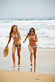 Two women wearing bikinis and summer hat on the beach