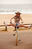 A girl wearing a hat sitting on a bike with her legs outstretched