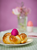 A coloured Easter egg in a bread wreath nest on an Easter table