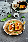 Close up of smoked salmon toasts on plate with soft goat cheese and basil over grey concrete table background