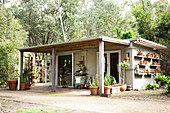 Holzhäuschen im Garten mit Vordach und viel Platz für Kübelpflanzen und Blumentöpfe