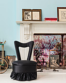 Black easy chair in front of marble fireplace decorated with pictures and sculptures