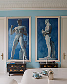 Zwei große gerahmte Fotografien von antiken Statuen vor himmelblauer Wand