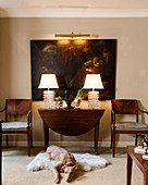 Dog lying on sheepskin rug in front of drop-leaf table and painting on wall